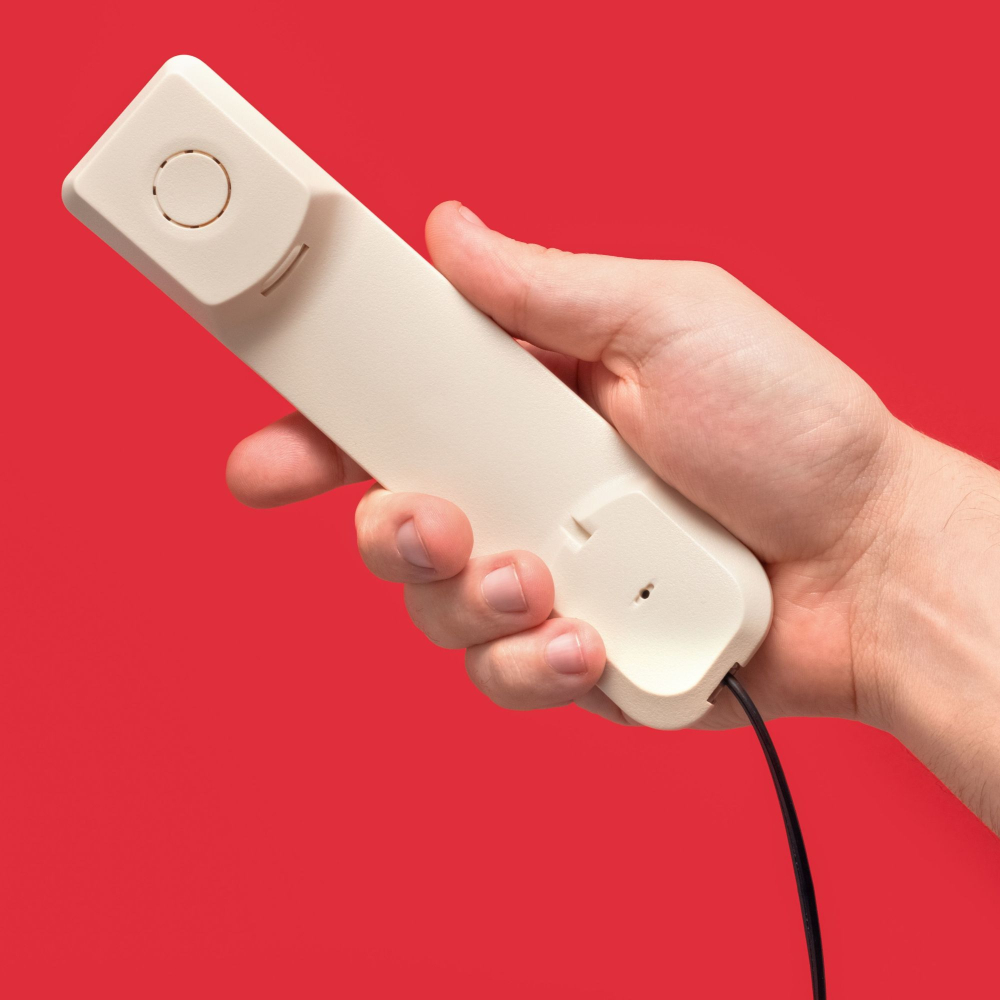 person holding an old style telephone with a red background